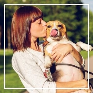 Woman holding and kissing beagle